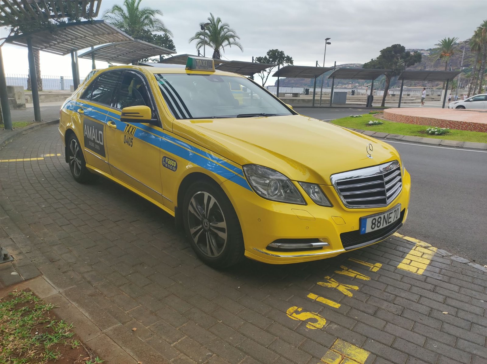 Táxi Mercedes amarelo da Vasco Táxis junto à marginal da Ribeira Brava